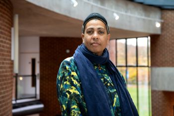 Portrait head and upper body shot of Helen Cammock with interior of Attenborough Centre for the Creative Arts in the background