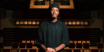 Jordi Carter in a black shirt sitting on a chair in an auditorium.
