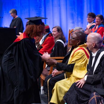 A graduate greeting Baroness Valerie Amos on stage