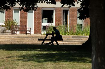 Person sitting on bench outside Arts A building