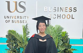 Manni Li in the Business School Jubilee building stood in front of the Business School sign