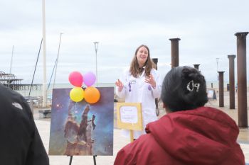 A scientist in a lab coat in front of a photograph of space