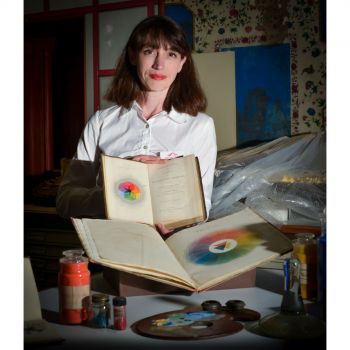 Photograph of Alexandra Loske smiling for camera holding books on colour