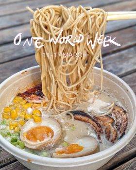 Bowl of Ramen noodles with chop sticks pulling noodles up and soft boiled egg cut in half