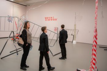 Young men showing their family around the exhibition of Jesse Darlings work