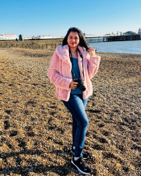 Woman standing on a pebble beach in a pink coat