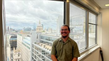 A man standing by an office window looking out towards St Paul's Cathedral, London