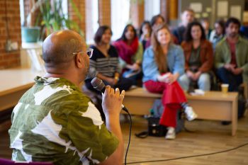 An attendee wearing a green and white shirt speaks to the audience