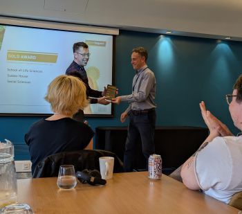 Dr Matt Montgomery hands the award to a smiling James Mudd in the Bramber House Conference Centre