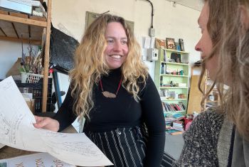 Rachael sat at table with artist Ottilie Hainsworth in studio, discussing story mapping workshop ideas