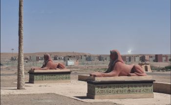 two Egyptian statues next to each other in a desert