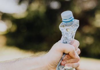 Man's hand squeezing a used plastic bottle