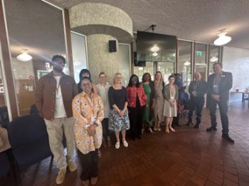 Mixed group of staff including Ghana visitors, EDI team, Associate Deans and senior leaders standing together in a dining space.