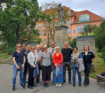 A photograph of all presenters standing in a group outside Charles University in Prague smiling for the camera