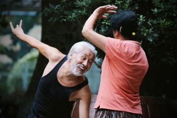 An image of two Chinese people smiling whilst practising Tai Chi