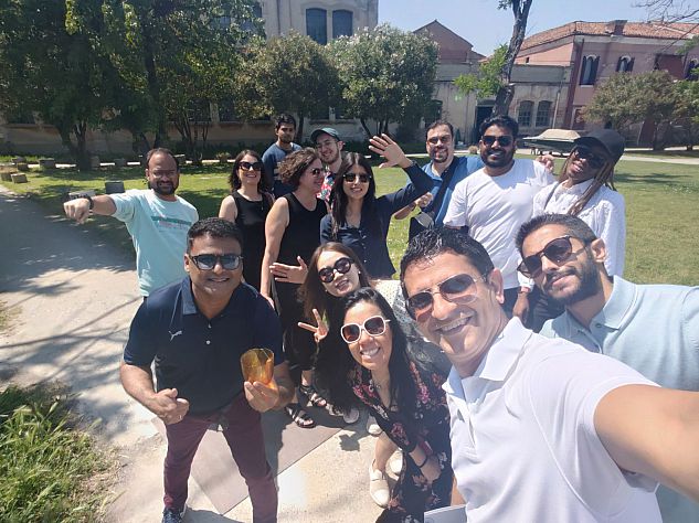 MBA students outside the Nason Moretti glass factory on some grass, all posing with MBA director Zahira Jaser and deputy director Claire Tingsager