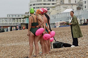 Photo of Ali Ramsey directing swimmers on brighton beach. The swimmers are holding bright pick floatation devices.
