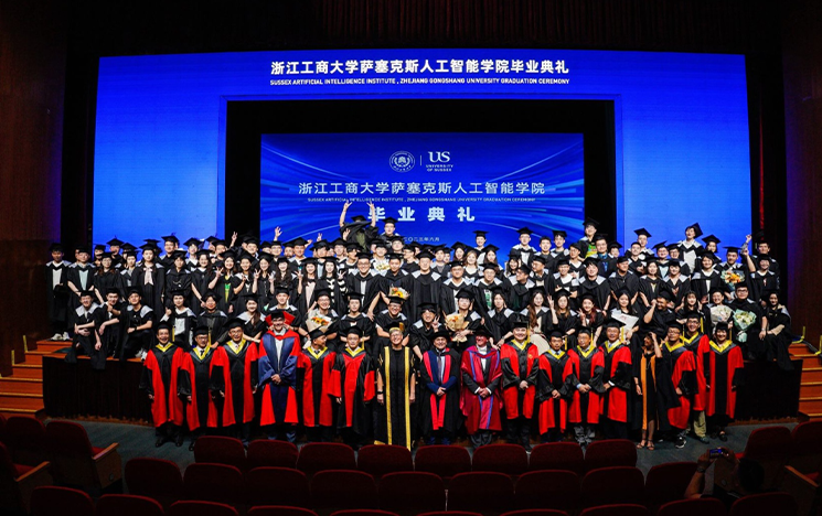 A group of graduates standing on a stage with a blue backdrop behind them.